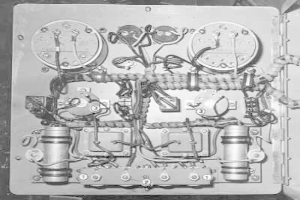 Schwarzes und weißes Foto eines Heterodyn-Empfängers mit einer Leiterplatte und angeschlossenen Drähten in einem Raum.