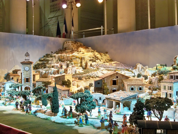 Ein detailliertes Miniatur-Modell einer Krippe, das in einem Museum ausgestellt wird und Figuren, Strukturen und Beleuchtungselemente enthält.