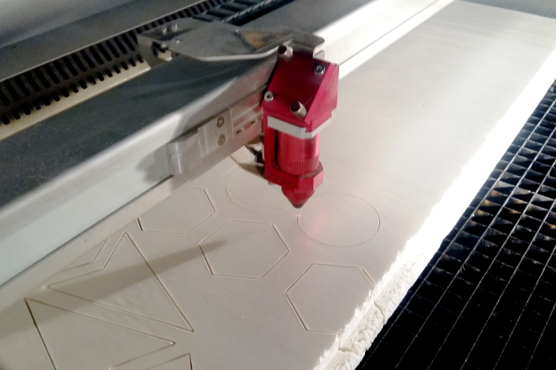 Eine CNC-Maschine verwendet einen Laserschneider, um ein Metallstück präzise zu schneiden, wobei der Laser ein helles Licht aussendet.