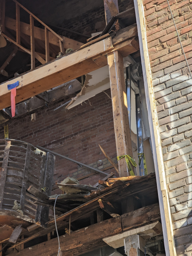 Ein teilweise abgerissenes Gebäude mit verstreuten Holzplanken und Trümmern, zerbrochene Fenster und Türen, was auf den Abriss hinweist.