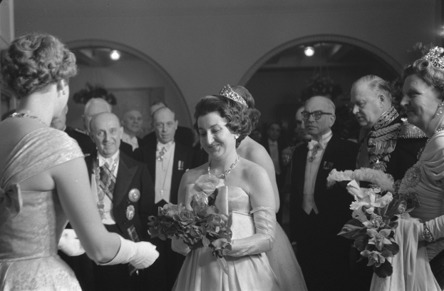 Schwarzes und weißes Foto von Queen Elizabeth II und Prinz Philip, Duke of Edinburgh, an ihrem Hochzeitstag, die Kronen tragen und Blumensträuße halten, umgeben von einer Gruppe von Menschen.