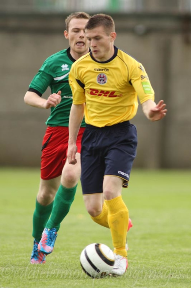 Zwei Männer beim Fussballspielen auf einem grünen Feld mit einem Ball, mit einem unscharfen Hintergrund und Text unten.