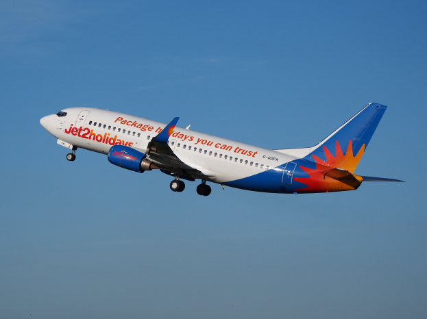 Ein Jet2holidays Airbus A320-200-Flugzeug im Flug, mit einer weißen, blauen, orangen und roten Lackierung gegen einen blauen Himmel.
