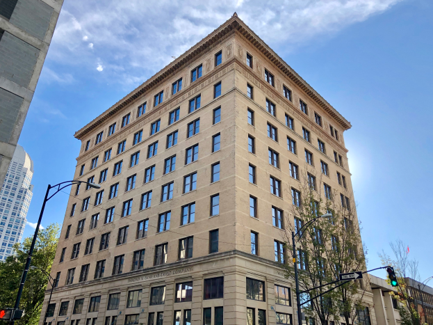 Ein hohes Gebäude mit vielen Fenstern, das als Union Bank und First Company in Chicago bezeichnet wird, umgeben von Straßenlaternen, Verkehrspfosten, Verkehrssignalen, Kraftfahrzeugen, Bäumen und einem bewölkten Himmel.