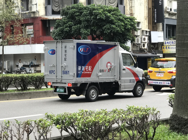 Ambulanz auf der Straßenseite neben einem Baum geparkt, mit Fahrzeugen, Gebäuden und anderen städtischen Elementen im Hintergrund.