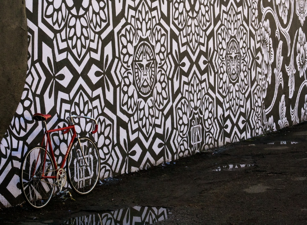 Eine Straße mit einem geparkten Fahrrad auf der linken Seite, einer bemalten Wand in der Mitte und einer Outdoor-Szene.