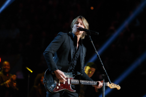 Keith Urban performs auf der Bühne im Joint im Hard Rock Hotel & Casino in Las Vegas, spielt Gitarre mit einem Mikrofon und Bandmitgliedern im Hintergrund bei gedämpftem Licht.