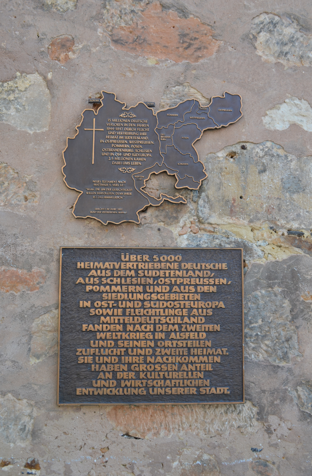 Eine Metalltafel an einer Steinwand mit einer Karte von Deutschland und einer Inschrift.
