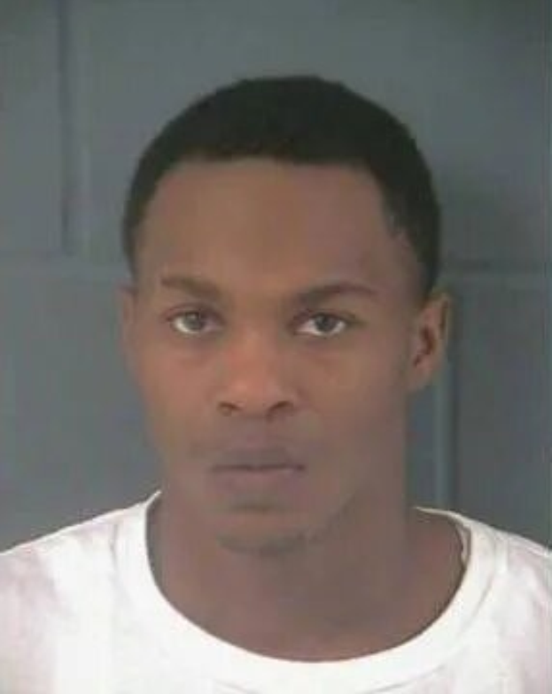 Ein Foto eines Mannes in einem weißen T-Shirt vor einem neutralen Hintergrund.