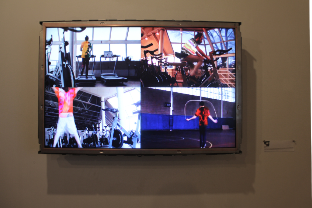 Ein an der Wand montierter Fernseher, der eine Gruppe von Menschen beim Sport zeigt.