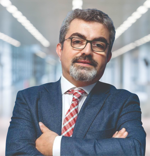 Ein Mann in Anzug und Krawatte mit verschränkten Armen, der eine Brille trägt und vor einem unscharfen Hintergrund steht, mit Text, der ihn als neu ernannten Marketingchef identifiziert.