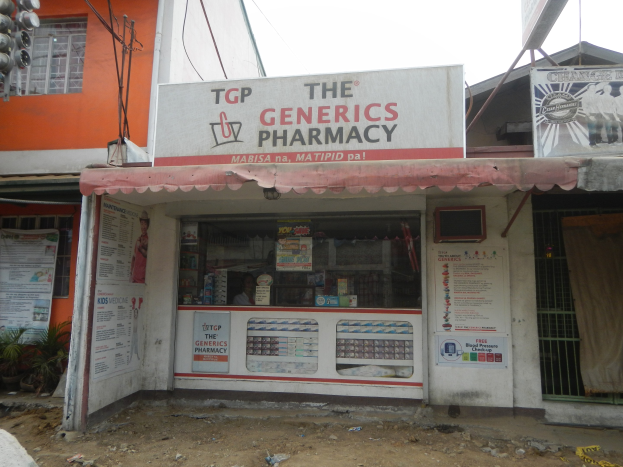 Außenansicht der 'Generics Apotheke' mit umliegenden städtischen Elementen und klarem Himmel.