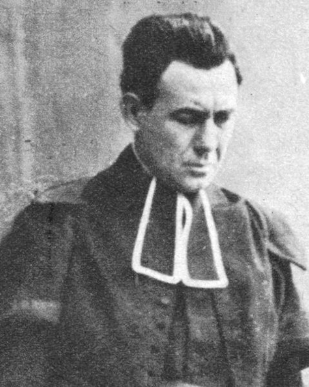 Ein Schwarz-Weiß-Foto eines Mannes in Priesterkleidung, der als erster Mann in die Vereinigten Staaten gewählt wurde, vor einer Wand mit ernster Miene.