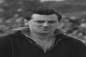 Ein Schwarz-Weiß-Foto des Schauspielers James Dean in einer Kapuzenjacke, der im Vordergrund steht mit einem unscharfen Hintergrund.