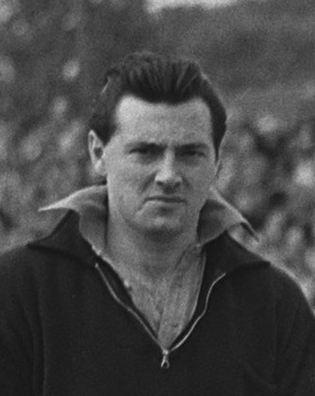 Ein Schwarz-Weiß-Foto des Schauspielers James Dean in einer Kapuzenjacke, der im Vordergrund steht mit einem unscharfen Hintergrund.