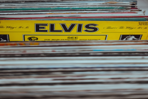Ein ordentlicher Stapel Elvis-Presley-Platten mit sichtbaren Titeln steht auf einem Tisch, der Hintergrund ist leicht unscharf.