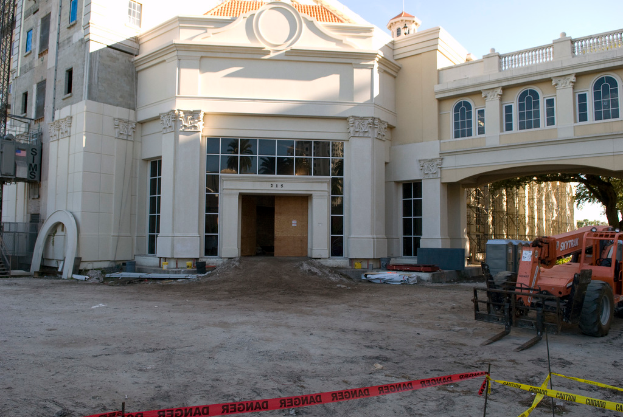 Ein Gebäude mit Glasfenstern, ein parkendes Fahrzeug in der Nähe und ein Baum im Vordergrund.