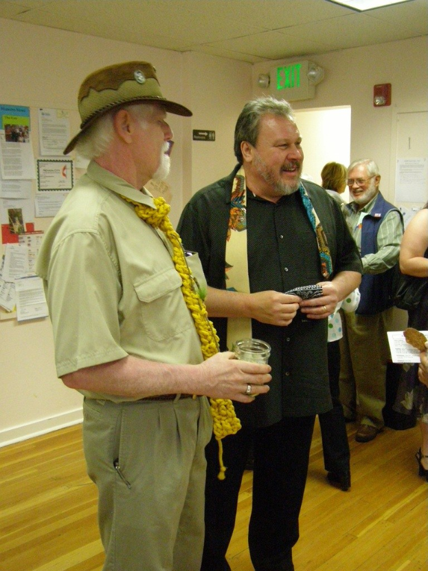 Alte Männer auf einem Holzboden mit Papieren an der Wand, eine Warnschild über einer Tür auf der rechten Seite und Deckenlampen.