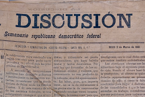 Ein gelblich vergilbtes, leicht zerknittertes Zeitungsblatt mit der schwarzen Aufschrift "Diskussion", das die Schlagzeile "Semanario Republicano Democrático Federal" trägt.