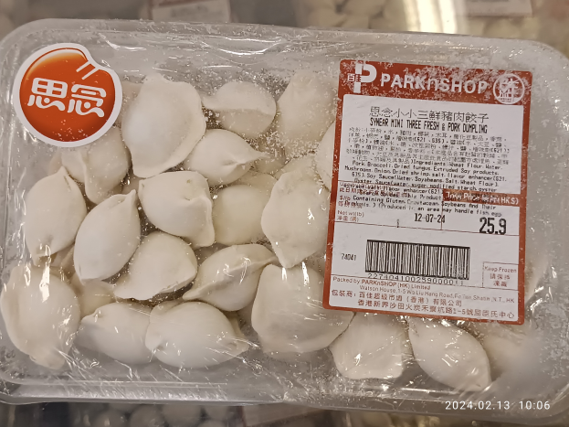 Ein Plastikbehälter mit einer Aufschrift 'Park Shop' enthält drei frische Schweineklöße, die mit einem Plastikdeckel abgedeckt sind und auf einem Tisch stehen.