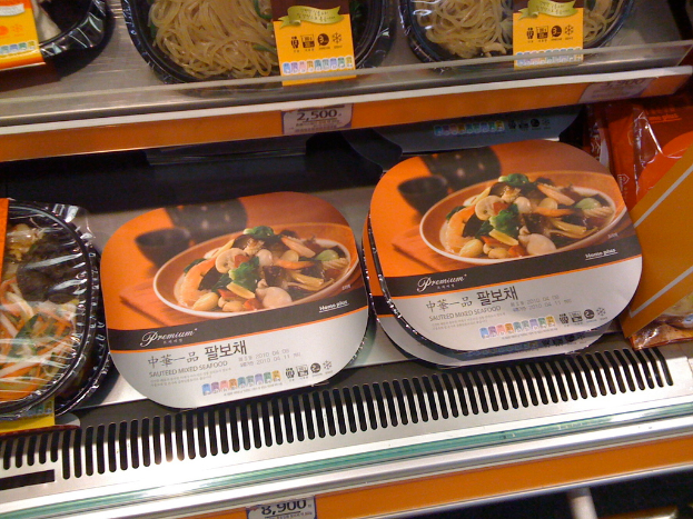 Lebensmittelboxen auf Regalen mit Preisschildern.