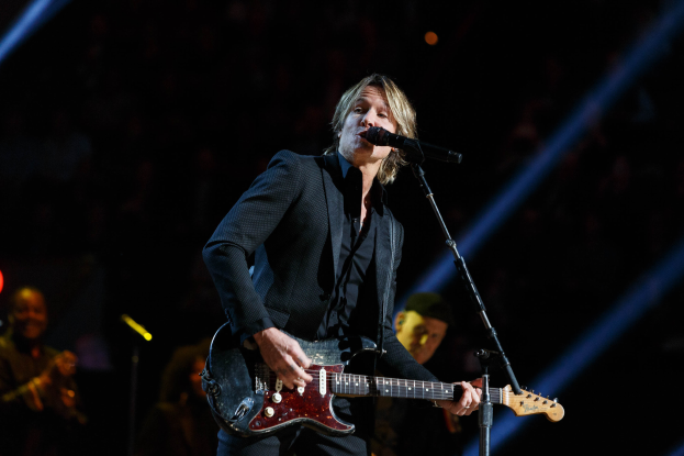 Keith Urban performs auf der Bühne im Joint in Las Vegas, spielt eine Gitarre mit einem Mikrofon davor und Musiker im Hintergrund, bei dunkler Beleuchtung.
