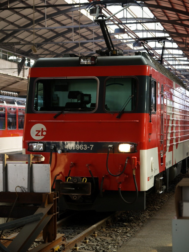 Ein Zug auf einem Gleis mit Steinen und Stangen in der Nähe und Text auf dem Zug.