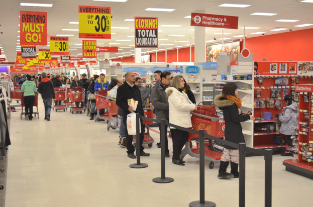 Ein volles Walmart-Geschäft mit Einkaufstaschen tragenden Kunden und Einkaufswagen, umgeben von Warenauslagen, Schildern und Deckenleuchten.