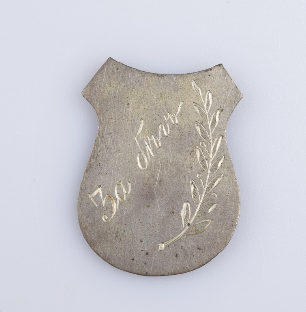 Silbernes Abzeichen mit Lorbeerkranz und der Aufschrift "50-jähriges Jubiläum" auf weißem Hintergrund.