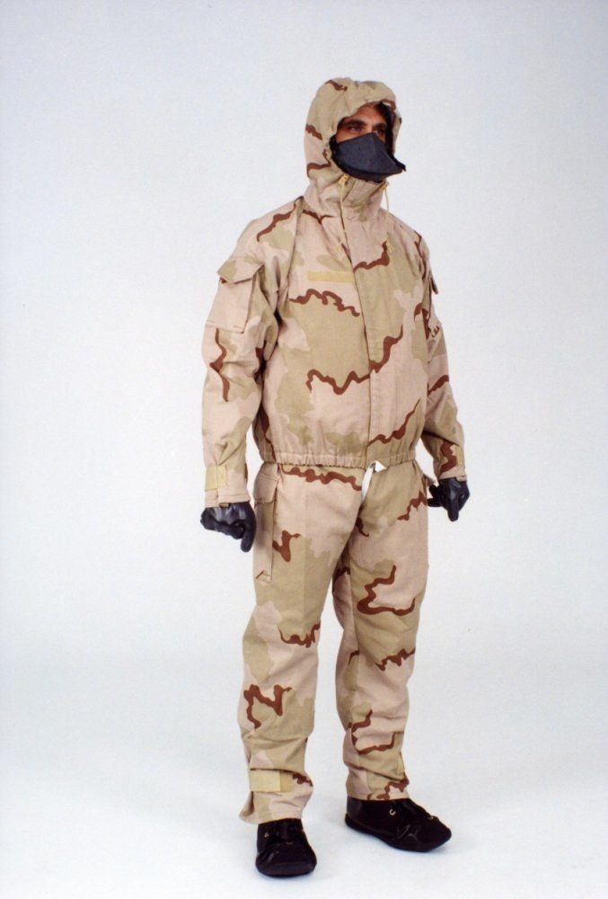 Mann in einem Tarnmuster-Schutzoverall und Kapuzenmaske vor einem weißen Hintergrund.