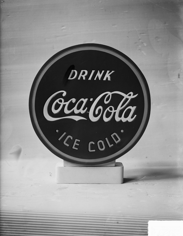 Schwarzes und weißes Foto eines Coca-Cola-Schilds mit dem Text "Trinken Sie Eisgekühlt."