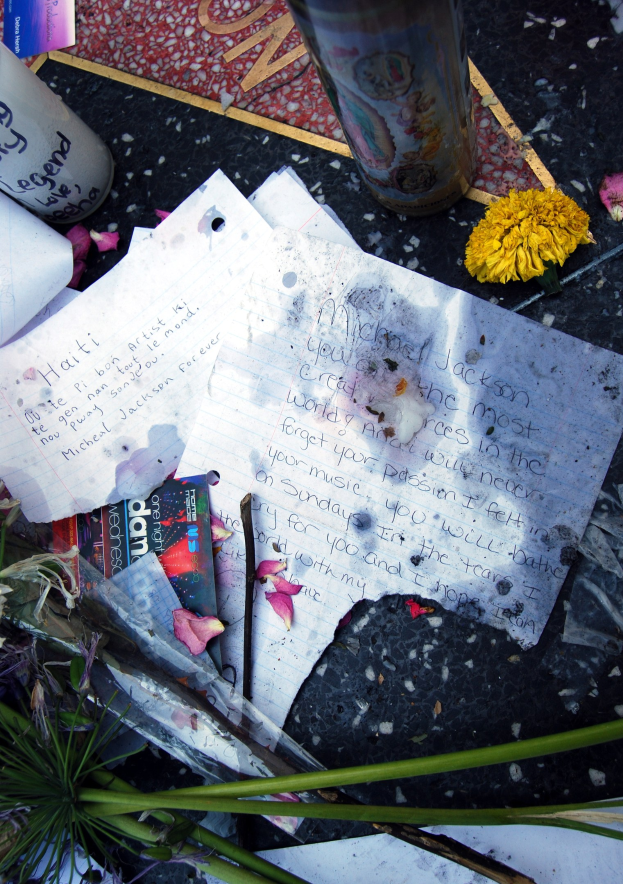 Gedenkstätte auf dem Hollywood Walk of Fame mit Blumen, Papieren, Büchern und einem Glas auf dem Boden.
