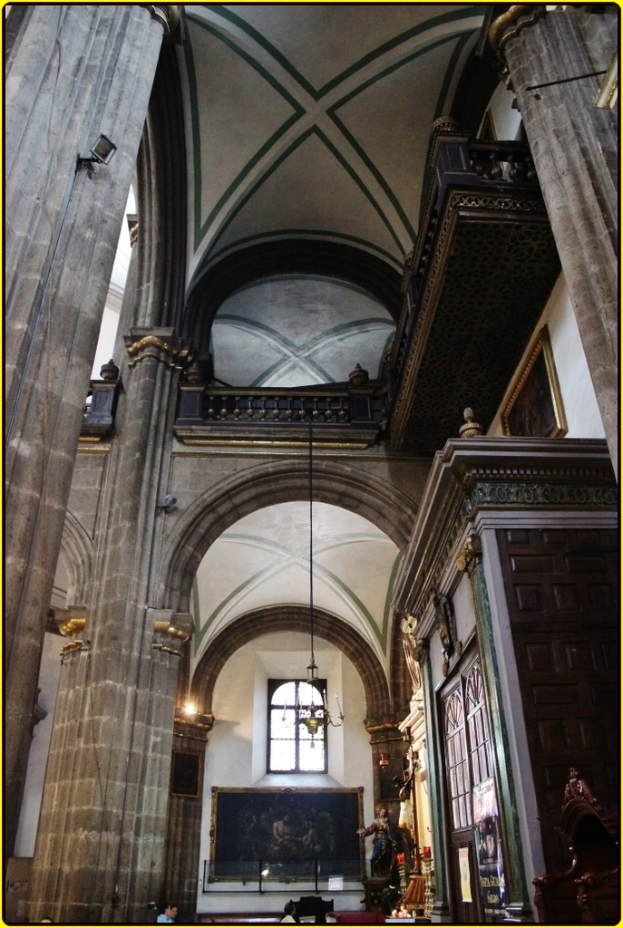 Ein Innenblick in einen Palast mit Schränken, beleuchteten Säulen, Wandskulpturen, einem großen Rahmenbild und einer von der Decke hängenden Lampe.
