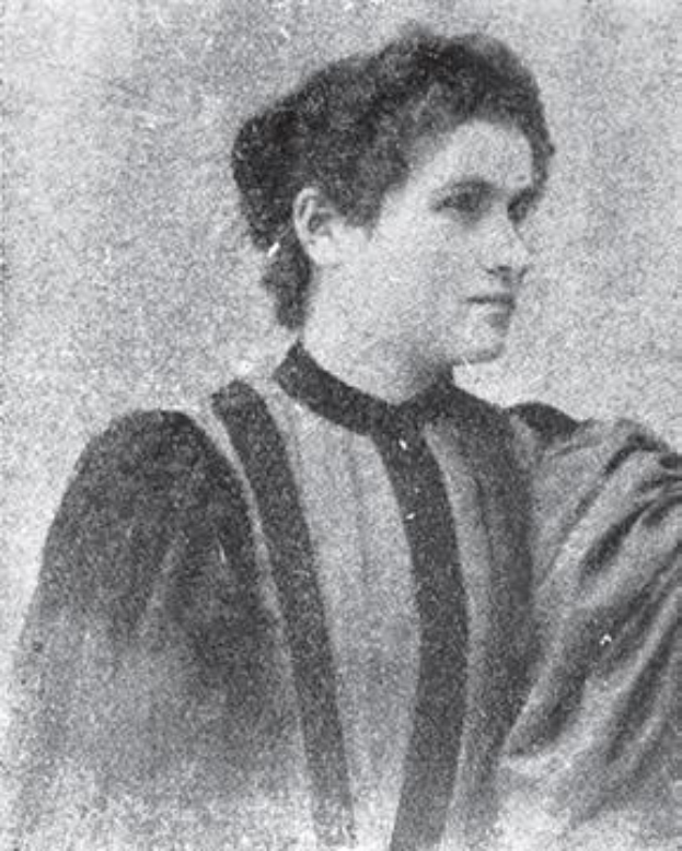 Ein Schwarz-Weiß-Foto einer Frau in einem gestreiften Hemd, mit zurückgebundenem Haar und einem ernsten Gesichtsausdruck, die in die Ferne schaut.