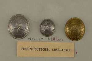 Drei silberne Polizeimarke mit Text darauf auf einer weißen Oberfläche.