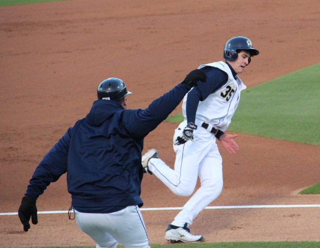 Zwei Personen mit Helmen und Handschuhen spielen auf einem Feld.