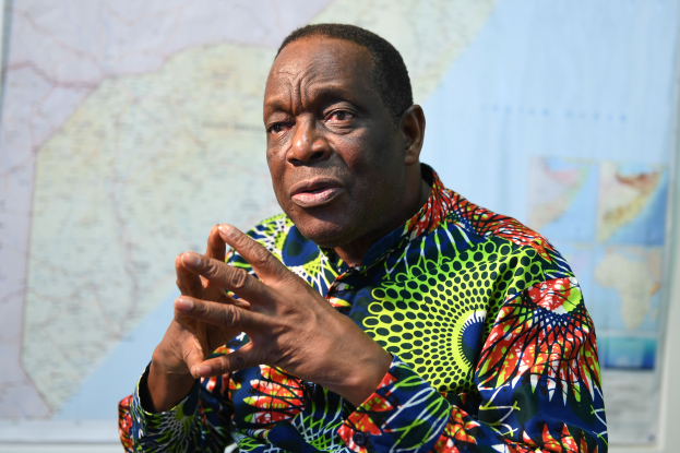 Ein Mann in einem bunten Hemd sitzt an einem Tisch, sieht besorgt aus, mit einer Karte im Hintergrund, wahrscheinlich aufgrund von Arbeitslosigkeit.