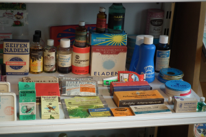 Ein Medizinschrank mit verschiedenen Flaschen, Schachteln und anderen Gegenständen sowie einem Regal mit verschiedenen Arten von Vorräten.