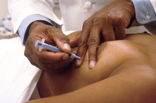 Ein Arzt in einem weißen Kittel setzt einem Patienten eine Spritze.