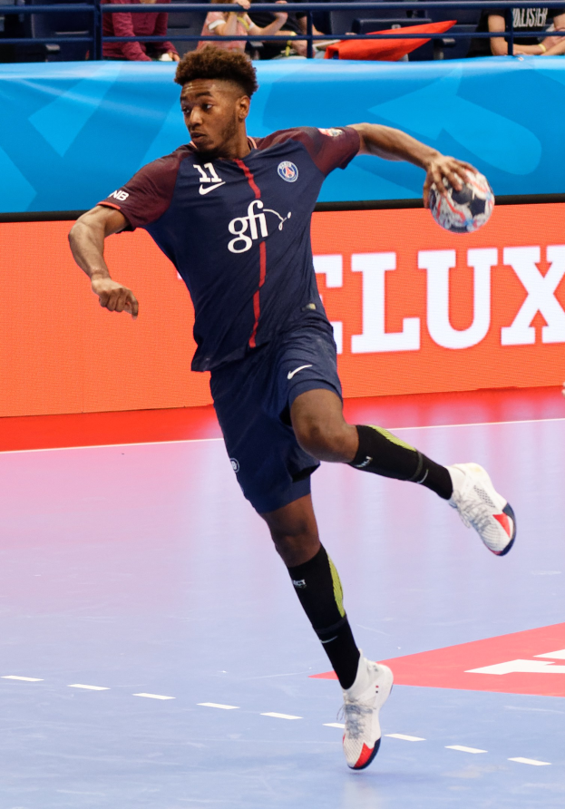 Ein Mann in einer blauen Uniform, identifiziert als Paris Saint-Germain, spielt Handball in einem Stadion während der Futsal-Weltmeisterschaft 2019, mit Zuschauern im Hintergrund.