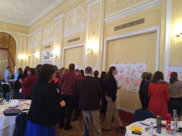 Eine Gruppe von Menschen, die Plakate und Charts auf einer Wand in einem Kunstmuseum betrachtet.