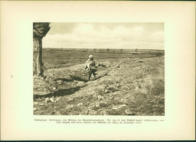 Ein Schwarz-Weiß-Foto eines Mannes, der einen Baumstamm auf einer Schotterstraße trägt, mit einem Baum auf der linken Seite und einem Himmel im Hintergrund, mit Text unten, der "Deutsche Soldaten in den Schützengräben des Ersten Weltkriegs" lautet.