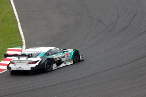 Ein Mercedes-AMG GT3 Rennauto auf einer Rennstrecke mit Text auf der Karosserie und Gras links.