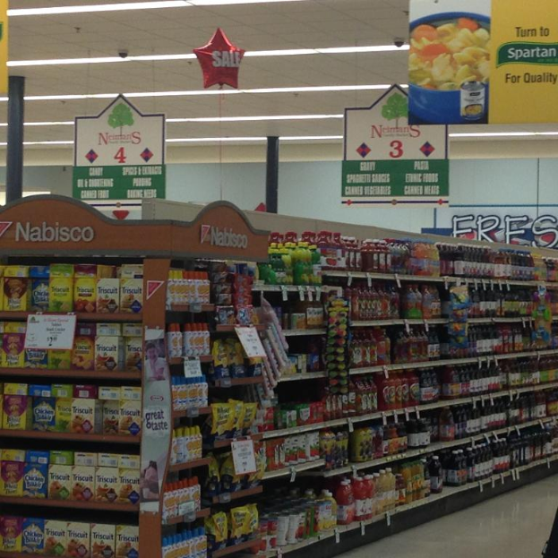 Ein Supermarktinneres mit sichtbaren Lebensmitteln, Deckenleuchten und hängenden Schildern.