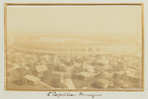 Altes Schwarz-Weiß-Foto eines Stadions, umgeben von Gebäuden, Bäumen und Strommasten mit Text unten.