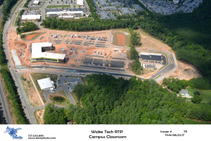 Luftaufnahme des Wake Tech RTP Campus Classrooms, mit Gebäuden, Bäumen, Straßen, Fahrzeugen und einem Text mit Logo unten.