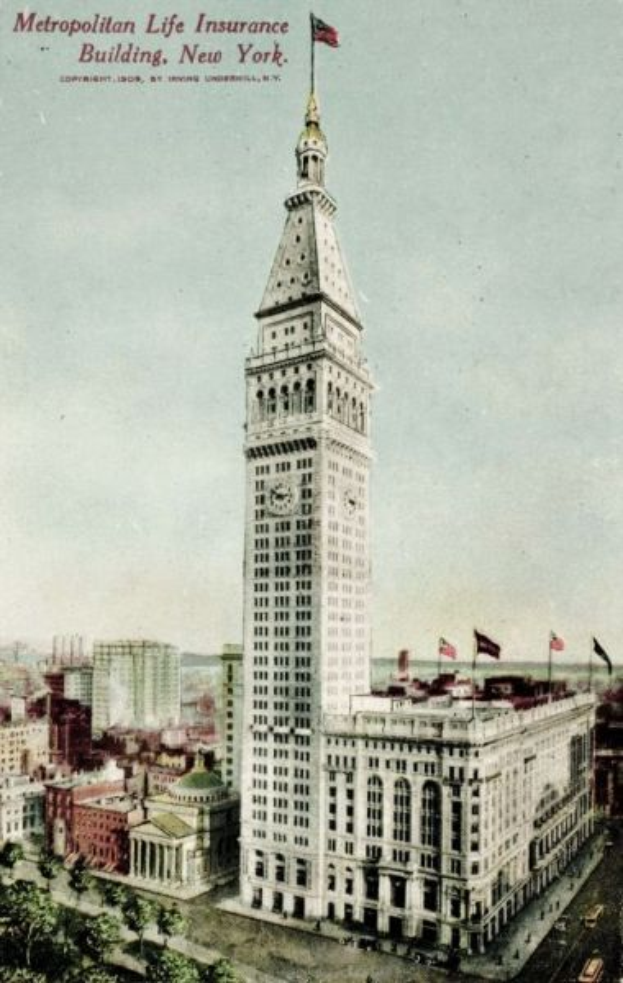 Alte Ansichtskarte des Metropolitan Life Insurance Building in New York City, die eine belebte Stadtlandschaft mit vielen Gebäuden, Bäumen und Fahrzeugen auf der Straße zeigt, mit dem Text "Metropolitan Life Insurance" oben.