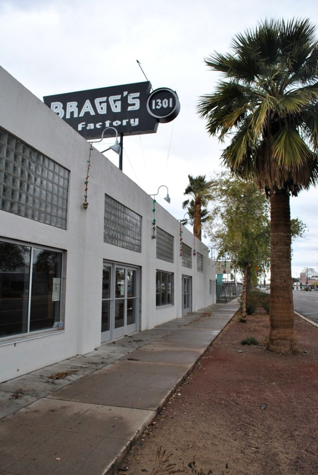Ein Gebäude mit einer Fahne, auf der 'Braggs Factory' steht, umgeben von Bäumen.